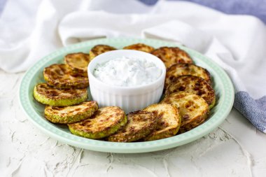 Ekşi krema soslu kızarmış kabak dilimleri. Beyaz arka planda akşam yemeği için otlu kızarmış kabaklar ve peçete.