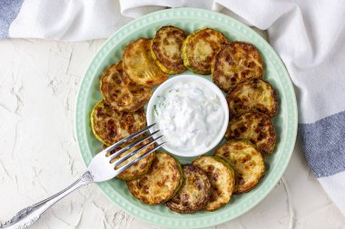 Ekşi krema soslu kızarmış kabak dilimleri. Beyaz arka planda akşam yemeği için otlu kızarmış kabaklar. Üst Wiev