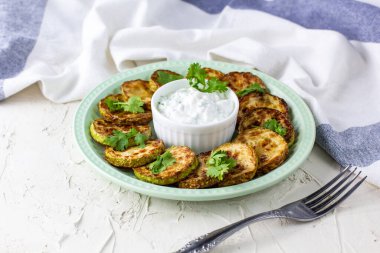 Ekşi krema soslu kızarmış kabak dilimleri. Beyaz arka planda akşam yemeği için otlu kızarmış kabaklar. Üst Wiev