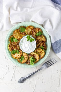 Ekşi krema soslu kızarmış kabak dilimleri. Beyaz arka planda akşam yemeği için otlu kızarmış kabaklar. Üst Wiev
