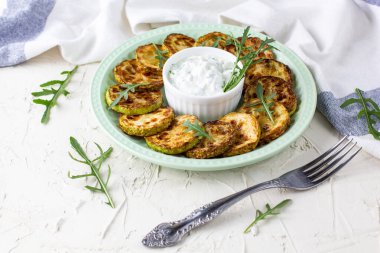 Ekşi krema soslu kızarmış kabak dilimleri. Beyaz arka planda akşam yemeği için otlu kızarmış kabaklar. Üst Wiev