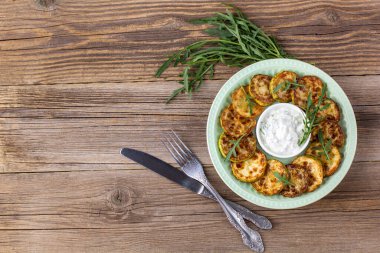 Ekşi krema soslu kızarmış kabak dilimleri. Doğal kahverengi ahşap arka planda akşam yemeği için otlu kızarmış kabaklar. Kopyalama alanı olan üst wiev