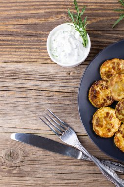 Ekşi krema soslu kızarmış kabak dilimleri. Doğal kahverengi ahşap arka planda akşam yemeği için otlu kızarmış kabaklar. Kopyalama alanı olan üst wiev