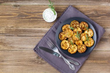 Ekşi krema soslu kızarmış kabak dilimleri. Doğal kahverengi ahşap arka planda akşam yemeği için otlu kızarmış kabaklar. Kopyalama alanı olan üst wiev