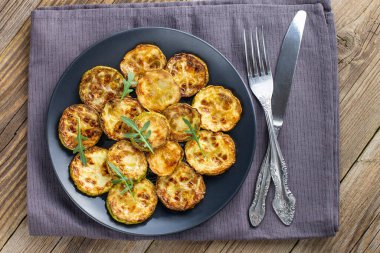 Ekşi krema soslu kızarmış kabak dilimleri. Doğal kahverengi ahşap arka planda akşam yemeği için otlu kızarmış kabaklar. Üst Wiev