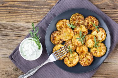 Ekşi krema soslu kızarmış kabak dilimleri. Doğal kahverengi ahşap arka planda akşam yemeği için otlu kızarmış kabaklar. Üst Wiev