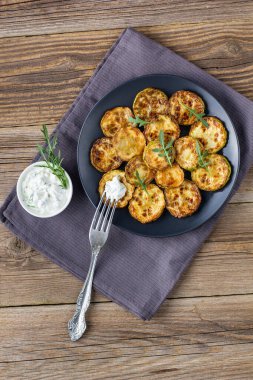 Ekşi krema soslu kızarmış kabak dilimleri. Doğal kahverengi ahşap arka planda akşam yemeği için otlu kızarmış kabaklar. Üst Wiev