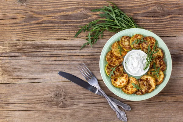 Ekşi krema soslu kızarmış kabak dilimleri. Doğal kahverengi ahşap arka planda akşam yemeği için otlu kızarmış kabaklar. Kopyalama alanı olan üst wiev