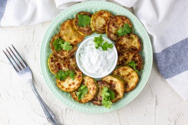 Ekşi krema soslu kızarmış kabak dilimleri. Beyaz arka planda akşam yemeği için otlu kızarmış kabaklar. Üst Wiev