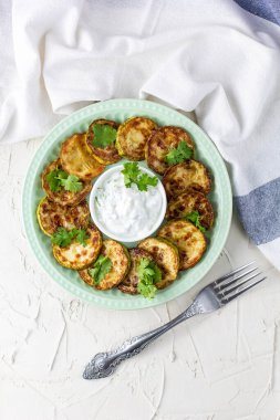Ekşi krema soslu kızarmış kabak dilimleri. Beyaz arka planda akşam yemeği için otlu kızarmış kabaklar. Üst Wiev