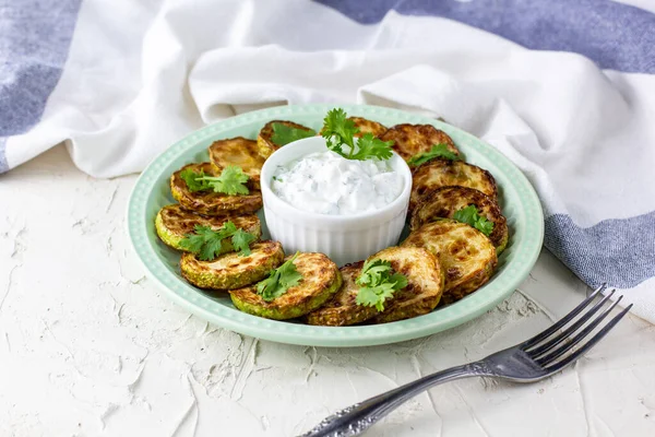 Ekşi krema soslu kızarmış kabak dilimleri. Beyaz arka planda akşam yemeği için otlu kızarmış kabaklar. Üst Wiev