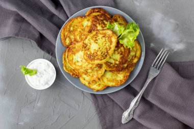 Ekşi krema soslu ve yeşillikli kabaklı börekler. Gri arka planda yeşil salatalı sebzeli gözleme. Üst görünüm