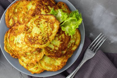 Ekşi krema soslu ve yeşillikli kabaklı börekler. Gri arka planda yeşil salatalı sebzeli gözleme. Üst görünüm