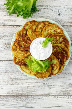 Ekşi krema soslu ve yeşillikli kabaklı börekler. Beyaz ahşap arka planda yeşil salatalı sebzeli gözleme. Kopyalama alanı olan üst görünüm