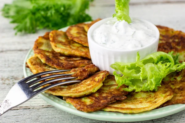 Ekşi krema soslu ve yeşillikli kabaklı börekler. Beyaz ahşap arka planda yeşil salatalı sebzeli gözleme..