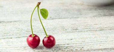 Açık beyaz zemin üzerinde yaprak olan iki kırmızı kiraz sancağının