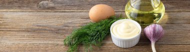 Doğal ahşap zemin üzerine sarımsak, yumurta, yağ ve bitkilerle mayonez sosu pankartı.