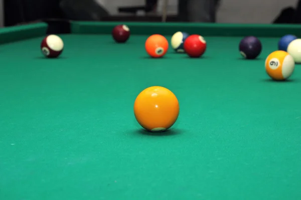 Billiard balls on green table and orange ball — Stock Photo, Image