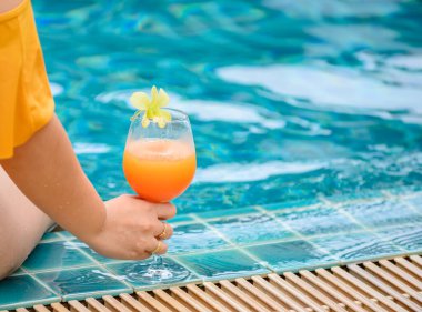 Kadın yüzme havuzunda bir bardak portakal suyu içti. Yaz tatili ve evde tek başına dinlenmek..