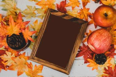Sonbahar ve Sonbahar sezonu. Boş fotoğraf çerçevesi ve tahta masada sahte akçaağaç yaprağı. Cornucopia hasatı ve Şükran Günü konsepti.