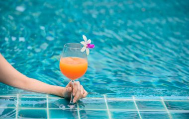Kadın yüzme havuzunda bir bardak portakal suyu içti. Yaz tatili ve evde tek başına dinlenmek..