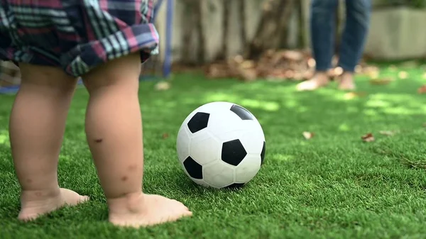 Kid play soccer with mom in garden at home. Family activity and lifestyle on holiday.