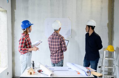 Mühendis ekibi inşaat sahasında tartışıp çalışıyor. Köy projesi ve emlak binasında teftiş.