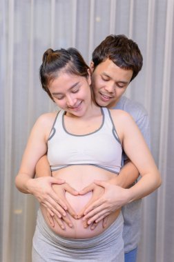 Aşk çifti ellerini kalp şeklini işaretlemek için kullanıyor. Hamileliğin aile yaşam tarzı.