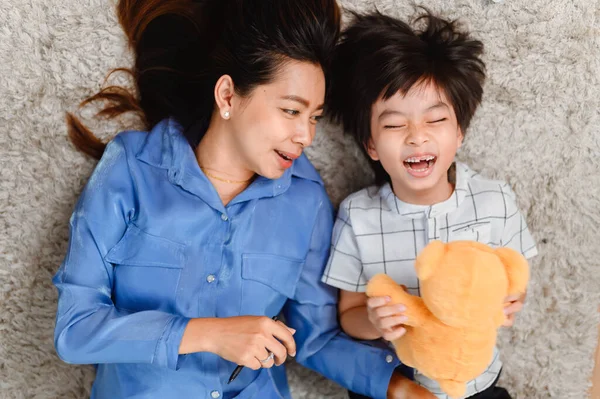 Evde Asyalı aile birliği. Anne ve çocuk oturma odasında birlikte doktorculuk oynuyorlar. Yaşam tarzı ve aile aktiviteleri.