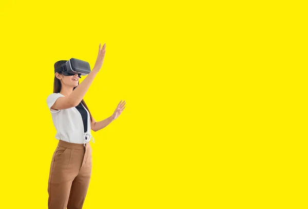 Asian woman using VR headset isolated on yellow background with clipping path. Wearing virtual reality headset for playing online game.