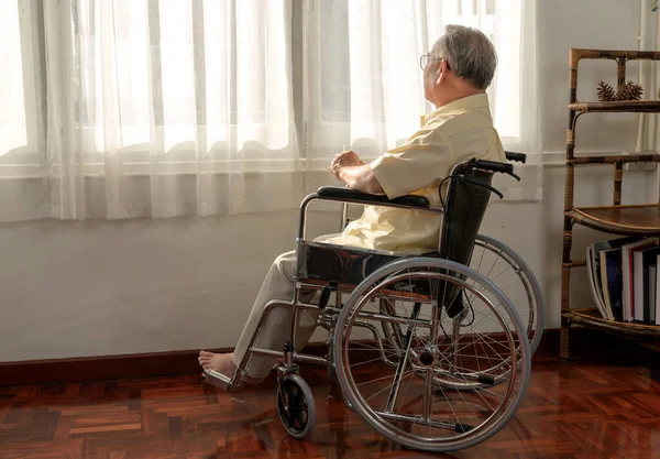Lonely Asian Senior man was sick and sitting on wheelchair. Retirement age lifestyle and stay at home alone.