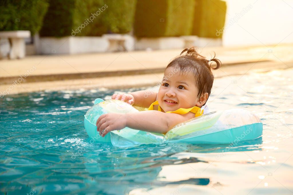 Kid swim in the swimming pool on summer holiday. Asian little girl lifestyle and relaxing.