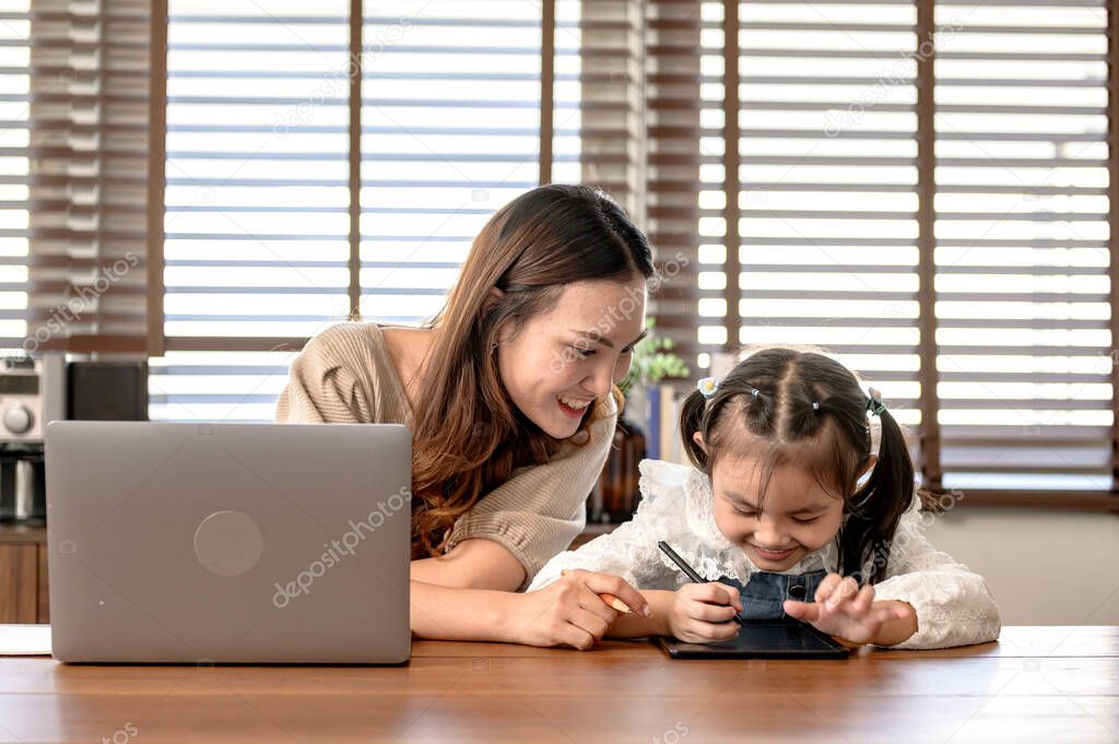 Mom working and teaching daughter for online learning at home. Family togetherness lifestyle and new normal after Covid-19.