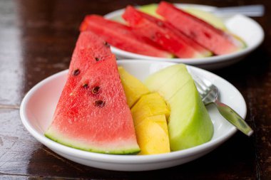 Taze kesilmiş karpuz ve ahşap kırsal arka planda mango.