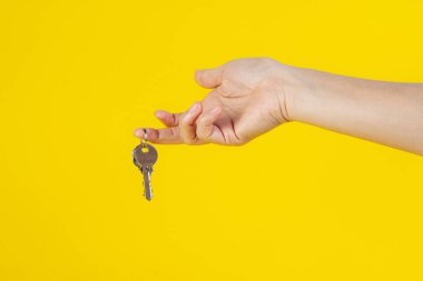 Sarı arka planda, elinde yüzük olan anahtar..