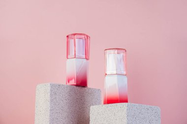 Siyah, boş, ince bir tüp. Rimel, dudak parlatıcısı, jöle, göz kalemi, yağ vs. Pembe arka planda şık dekorları olan kozmetik paketler..