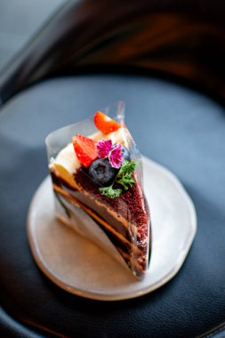 Limonata ile kaplanmış güzel bir yaban mersinli ve çilekli kek, bir tabakta servis ediliyor, arka fon olarak da bir kafe..