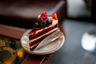 Limonata ile kaplanmış güzel bir yaban mersinli ve çilekli kek, bir tabakta servis ediliyor, arka fon olarak da bir kafe..