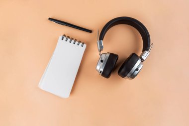 Defter masanın üstünde. Mesaj bırakmak için boş bir defter. Kalemler, kulaklıklar