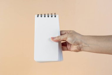 Krema arkaplanına karşı beyaz bir defter.