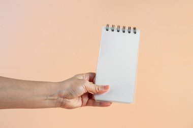 Krema arkaplanına karşı beyaz bir defter.