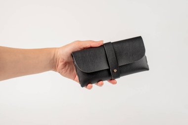 Beyaz bir arka planda, elinde siyah bir gözlük kılıfı..