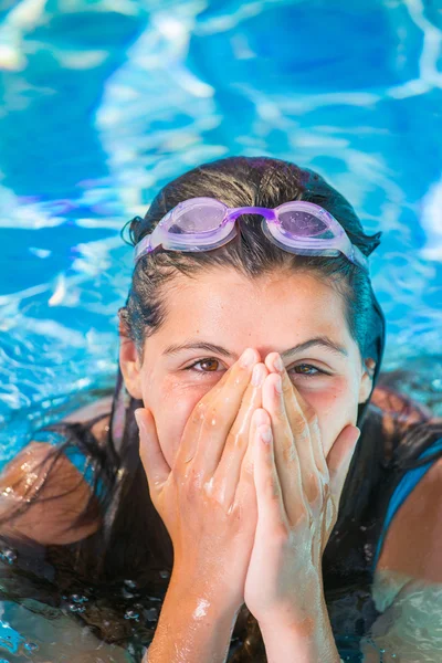 Улыбающаяся девушка в бассейне кладет руки перед носом — стоковое фото