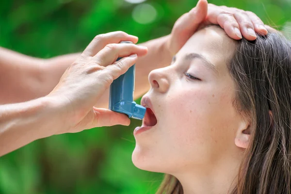 Potret seorang gadis menggunakan inhaler untuk asma dari tangan ibunya — Stok Foto