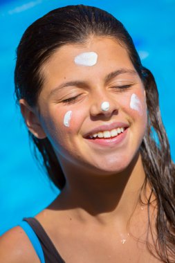 Genç kız gülümseyen yüze uygulanan güneş kremi korumak