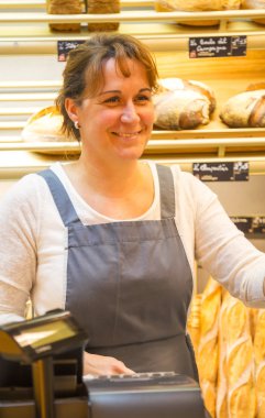 bir fırın ekmek satan bir önlük ile gülümseyen kadın