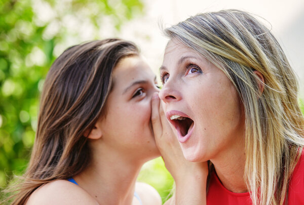 Teen whispering in the ear of her mother