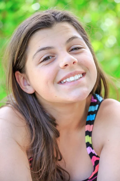 Krásná mladá dívka s úsměvem s krásné hnědé dlouhé vlasy izolován v zeleném pozadí — Stock fotografie