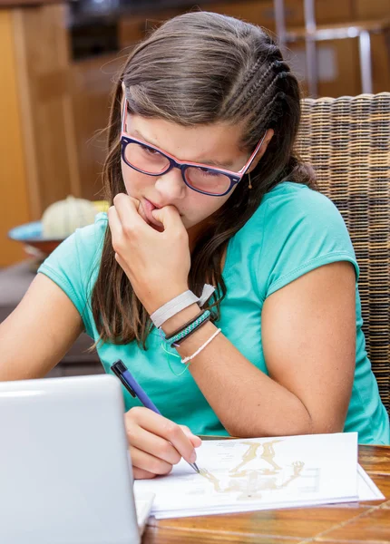Скерована дівчина-підліток намагається прикусити під час виконання її домашнього завдання — стокове фото