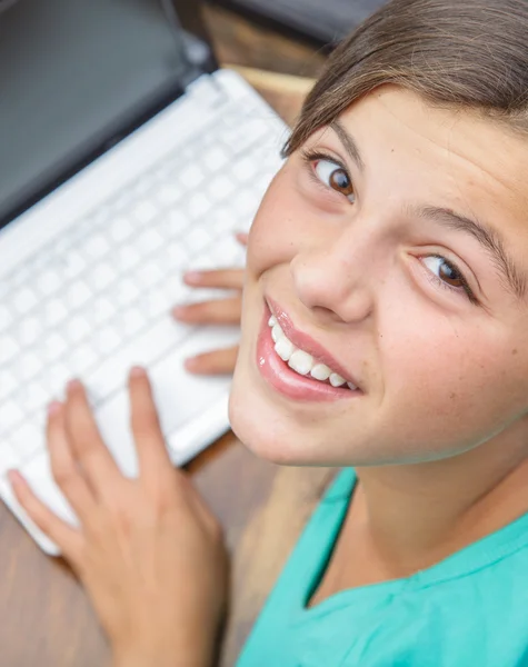 Крупним планом красива молода дівчина посміхається, хто друкує на клавіатурі комп'ютера, видно зверху — стокове фото